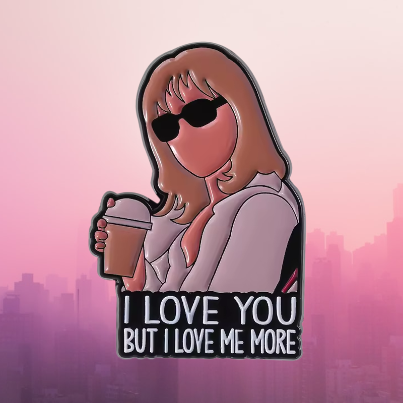 A die-cut enamel pin featuring a cartoon illustration of a woman with sunglasses holding a coffee cup, with the text 'I LOVE YOU BUT I LOVE ME MORE' at the bottom, shown against a pink city skyline background.