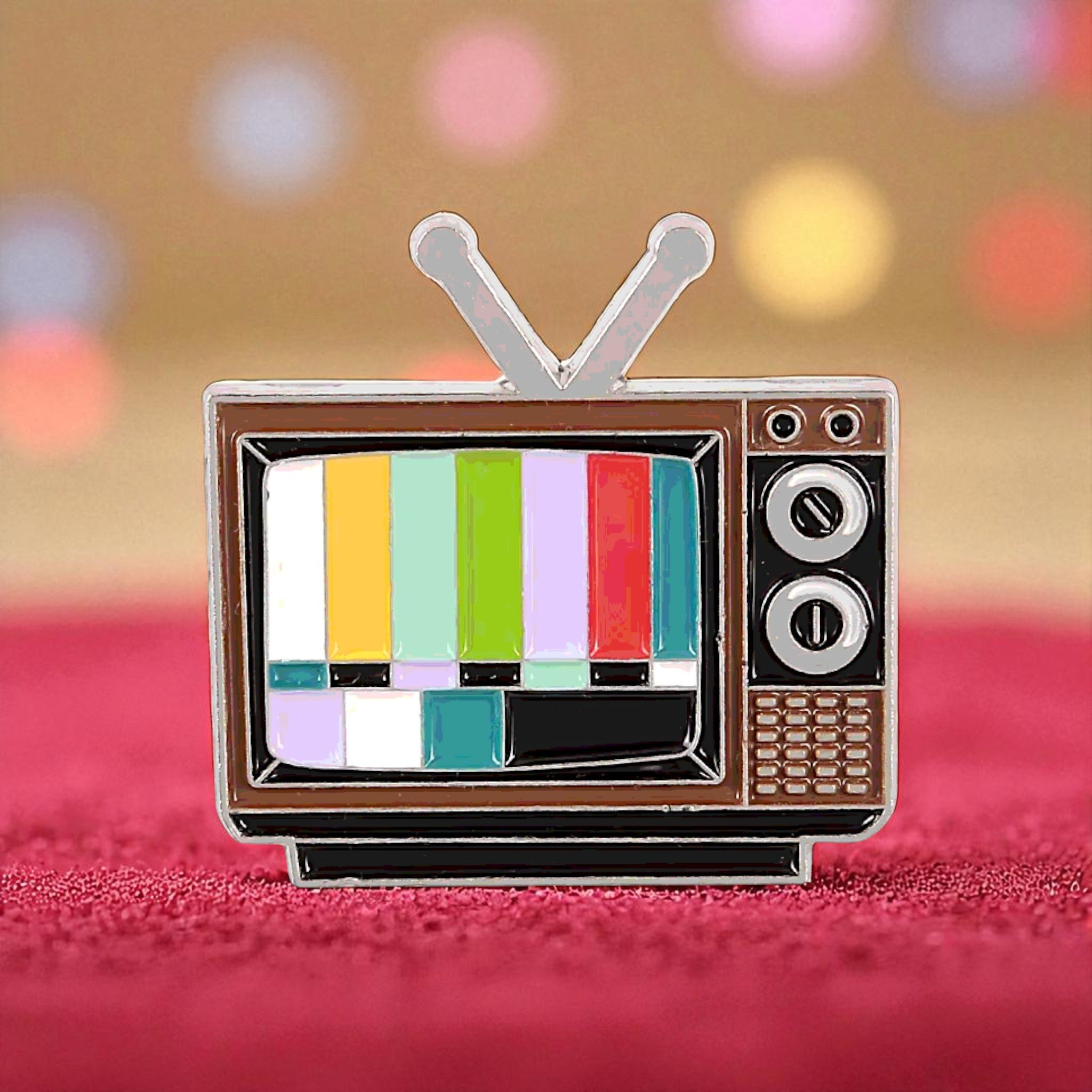 Vintage-style television enamel pin with color bars on a blurred background