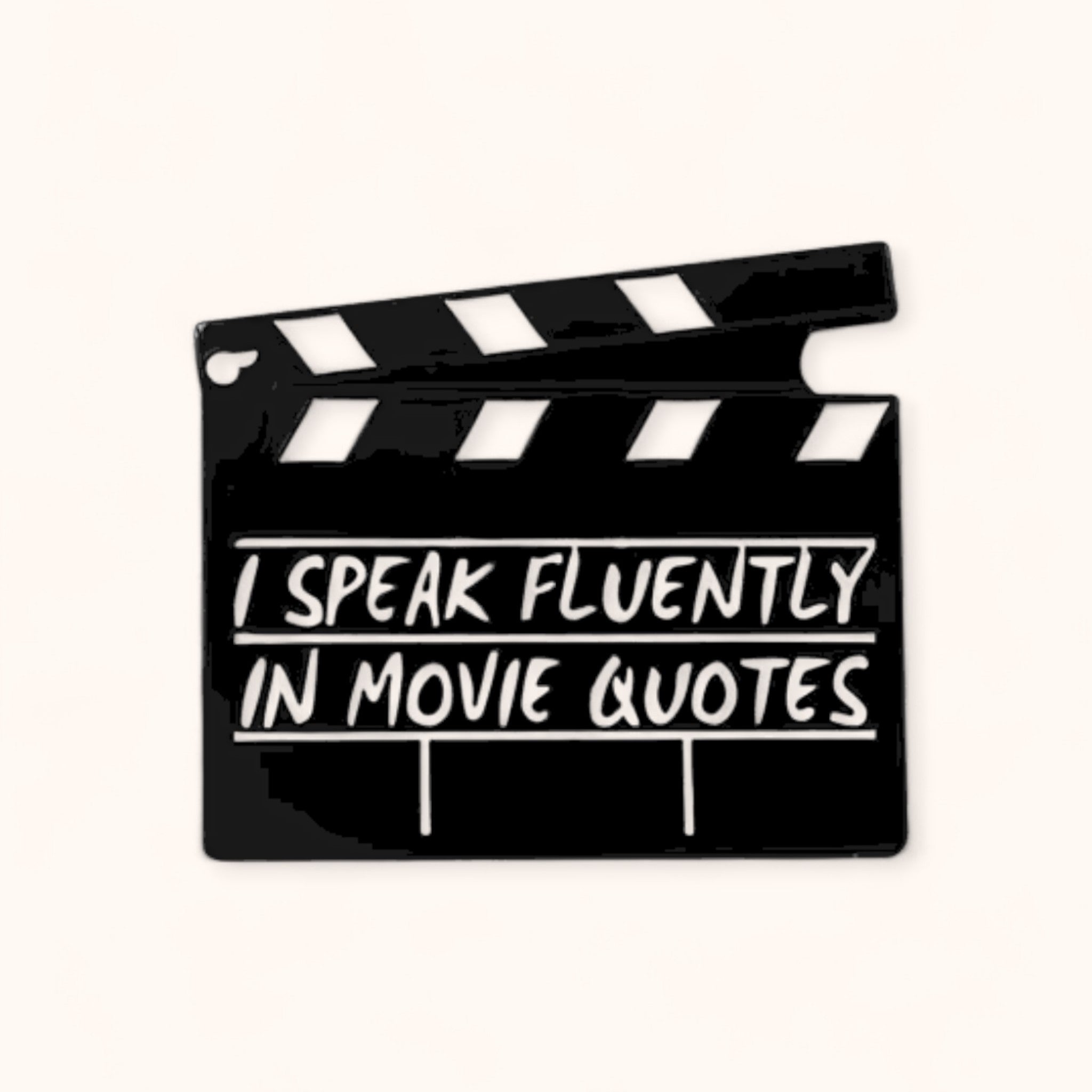 Clapperboard with 'I speak fluently in movie quotes' text on an enamel pin