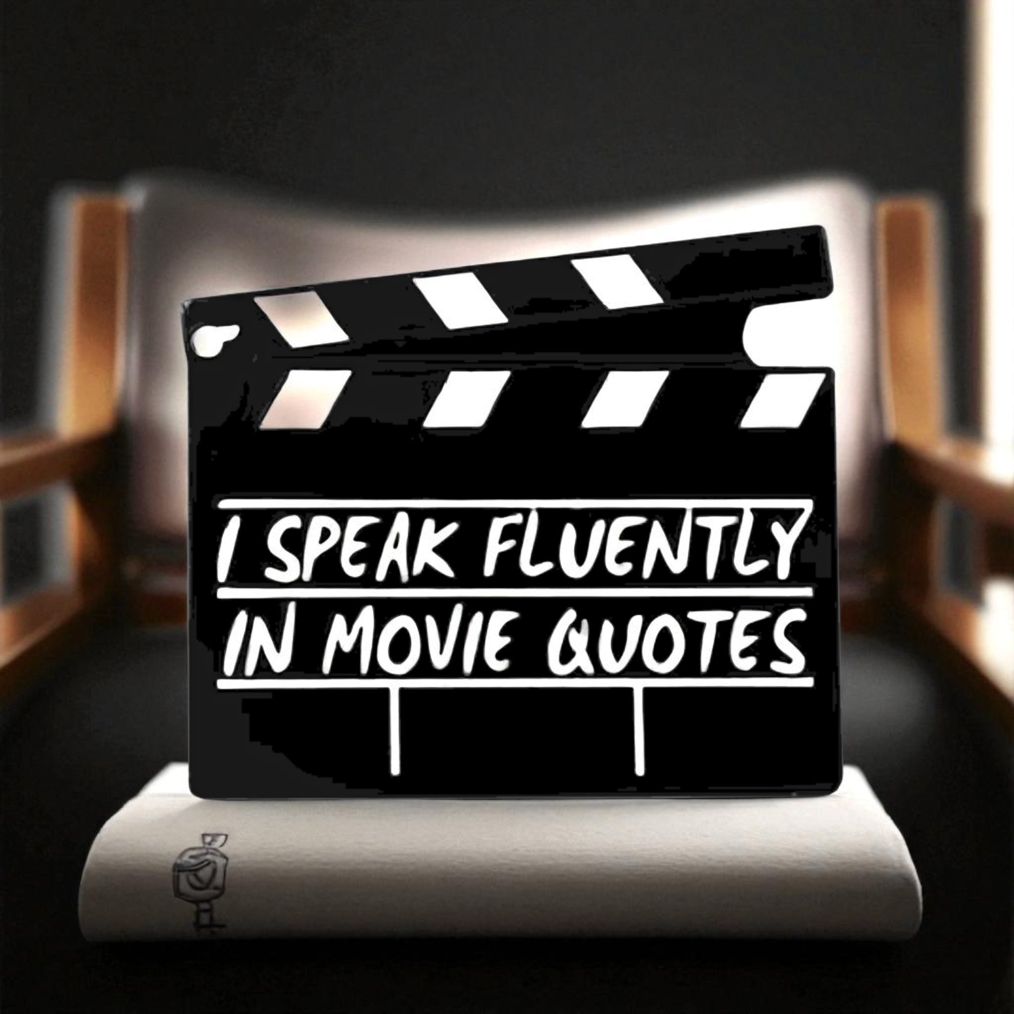 Clapboard with 'I speak fluently in movie quotes' text on a blurred movie theater background