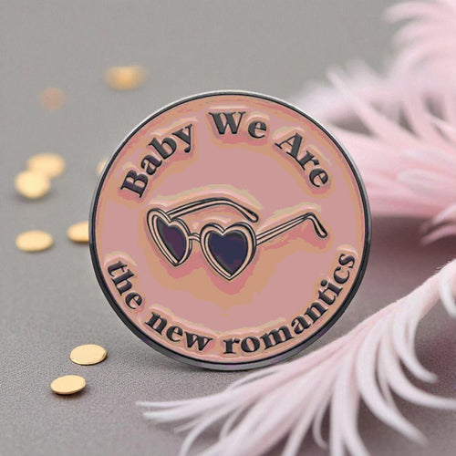 Pin with 'Baby We Are the New Romantics' text and heart sunglasses design on a gray background.