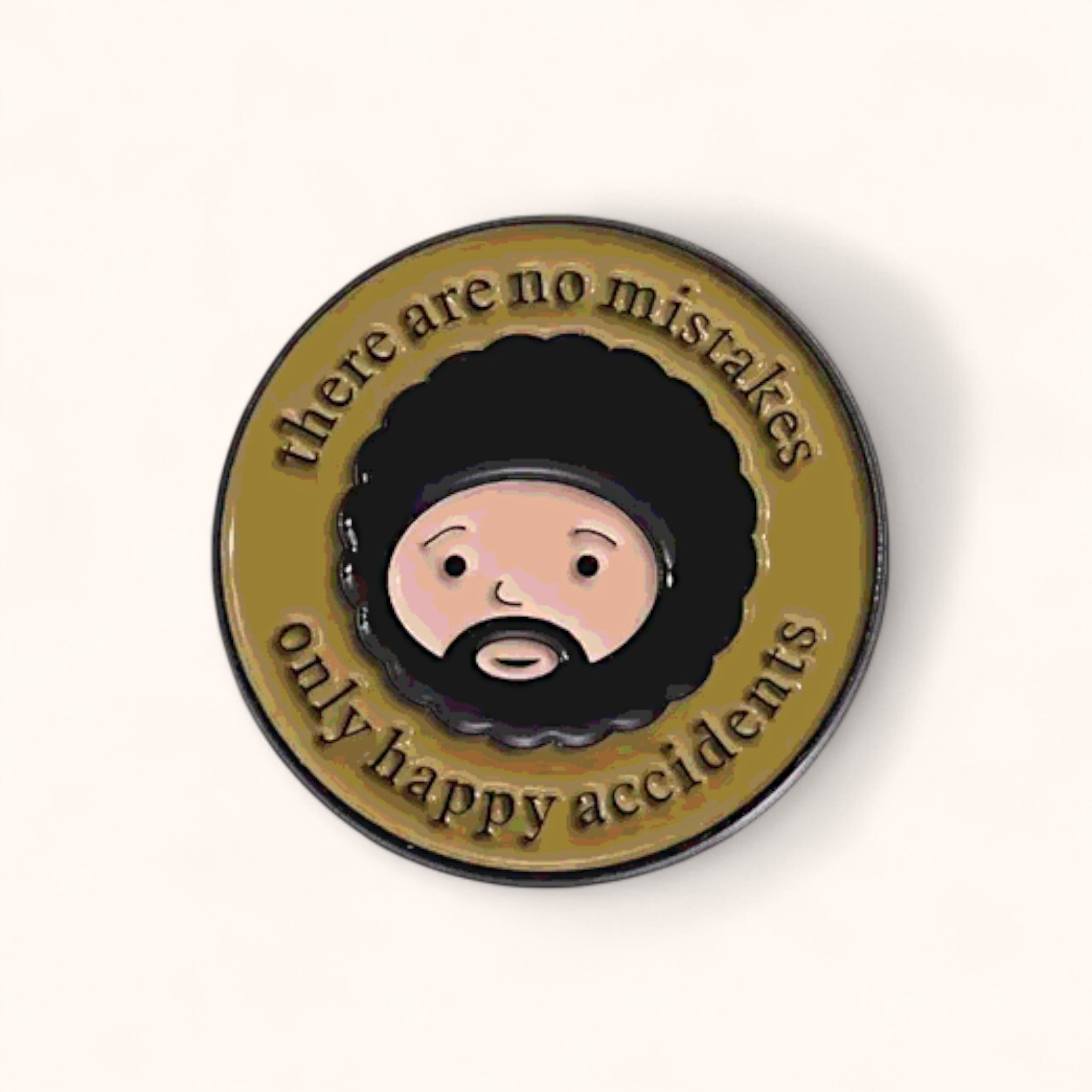 Circular badge with a cartoon face and text 'there are no mistakes only happy accidents' enamel pin