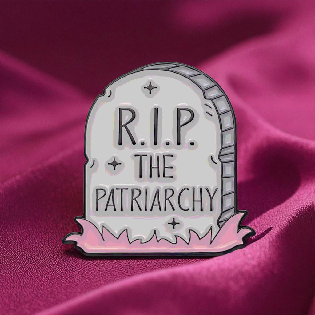 Enamel pin shaped like a tombstone with 'R.I.P. THE PATRIARCHY' text on a pink background