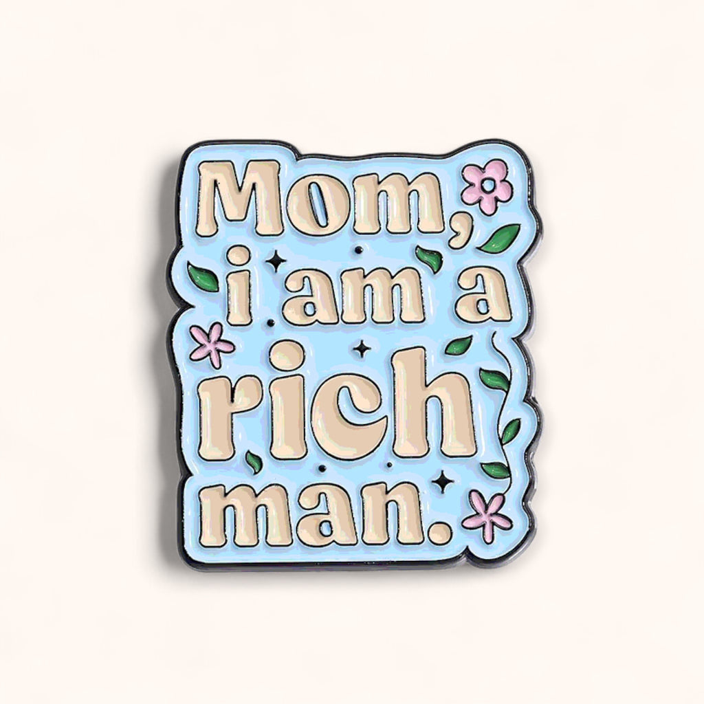 Enamel pin with text 'Mom, i am a rich man.' on a light blue background