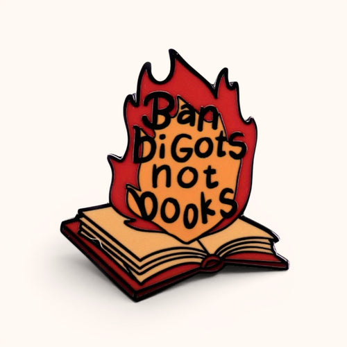 Enamel pin featuring an open book surrounded by flames with the words "Ban Bigots Not Books."